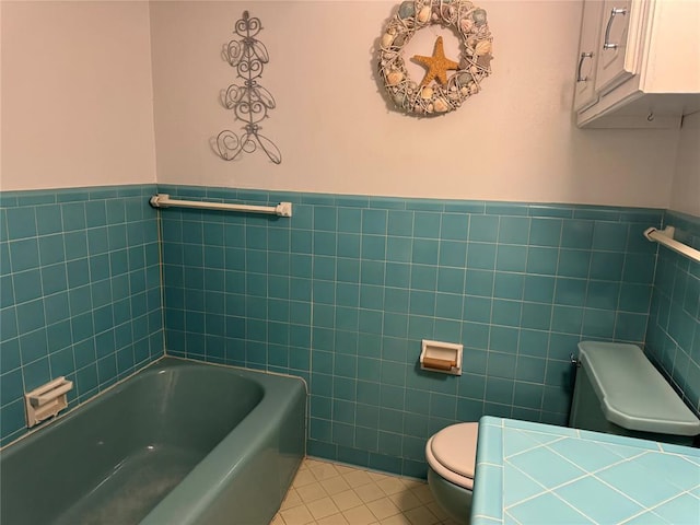 bathroom featuring tile patterned flooring, a bathtub, toilet, and tile walls