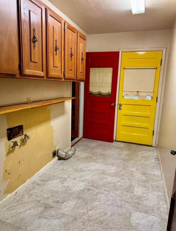 clothes washing area featuring hookup for a washing machine, cabinets, and a textured ceiling