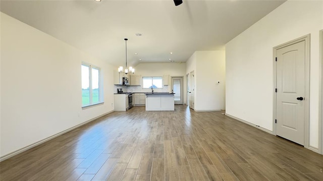 unfurnished living room featuring sink, a chandelier, and wood-type flooring