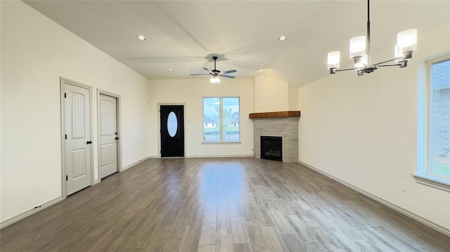 unfurnished living room featuring hardwood / wood-style floors, plenty of natural light, ceiling fan with notable chandelier, and a tile fireplace