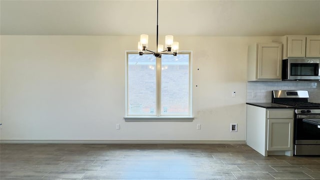 kitchen with pendant lighting, appliances with stainless steel finishes, tasteful backsplash, white cabinetry, and a chandelier