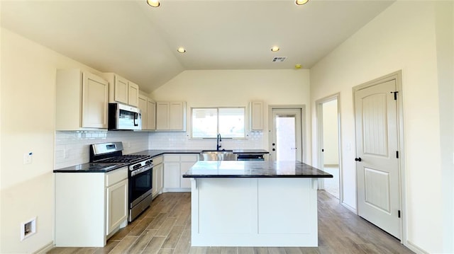 kitchen with stainless steel gas range oven, sink, white cabinets, a center island, and light hardwood / wood-style floors