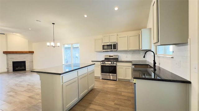 kitchen featuring white cabinetry, sink, decorative light fixtures, a kitchen island, and appliances with stainless steel finishes