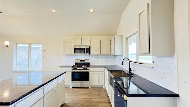 kitchen with stainless steel appliances, sink, light hardwood / wood-style flooring, white cabinetry, and lofted ceiling