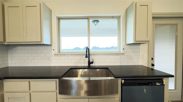 kitchen with dark stone counters, white cabinets, sink, stainless steel dishwasher, and tasteful backsplash