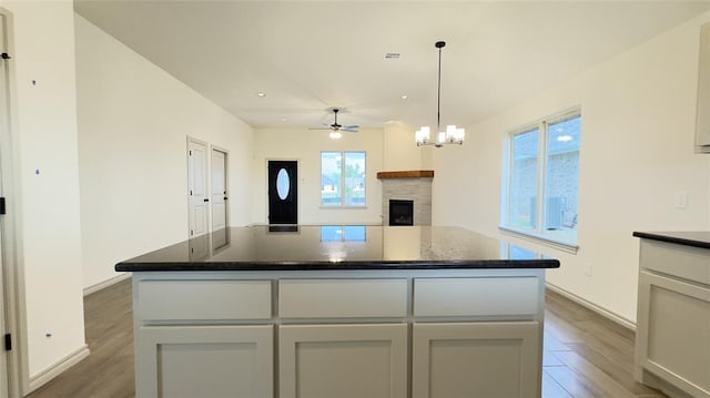 kitchen featuring white cabinetry, a kitchen island, wood-type flooring, and ceiling fan with notable chandelier