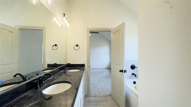 bathroom with vanity, a washtub, and vaulted ceiling