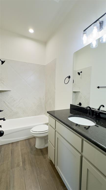 full bathroom featuring toilet, hardwood / wood-style floors, vanity, and tiled shower / bath combo