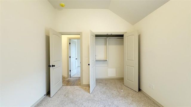 unfurnished bedroom with a closet, light colored carpet, and vaulted ceiling