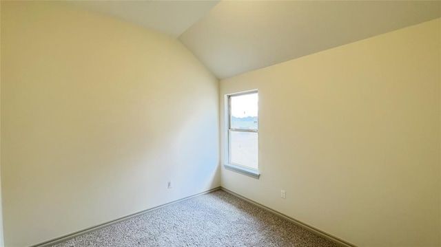 spare room featuring carpet flooring and lofted ceiling