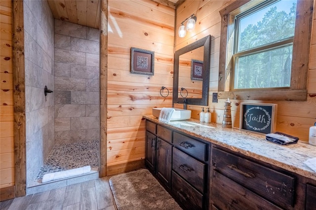 bathroom featuring wooden walls, vanity, and tiled shower