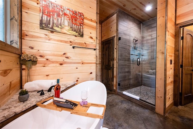 bathroom with concrete flooring, shower with separate bathtub, and wooden walls