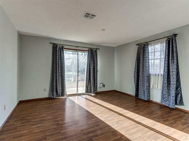 unfurnished room with a textured ceiling and dark hardwood / wood-style floors