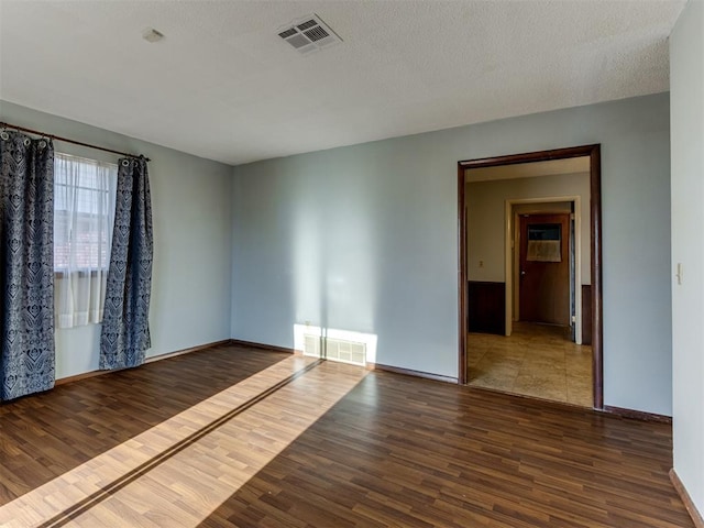 unfurnished room featuring a textured ceiling and dark hardwood / wood-style flooring