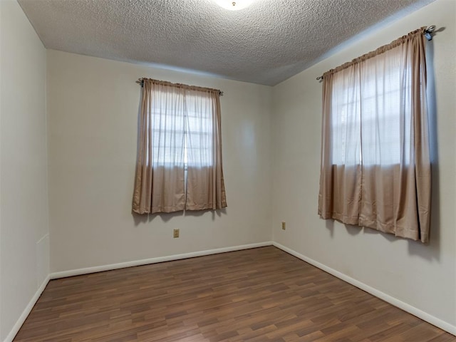 unfurnished room featuring a textured ceiling, a wealth of natural light, and dark wood-type flooring