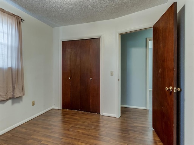 unfurnished bedroom with dark hardwood / wood-style flooring, a textured ceiling, and a closet