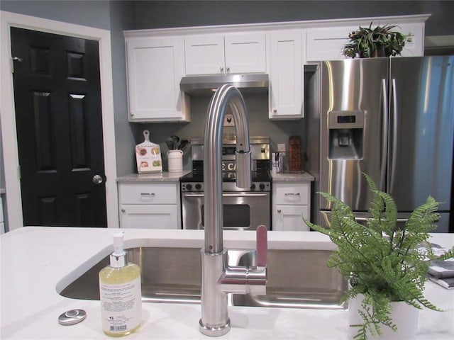 kitchen featuring under cabinet range hood, stainless steel appliances, and white cabinetry