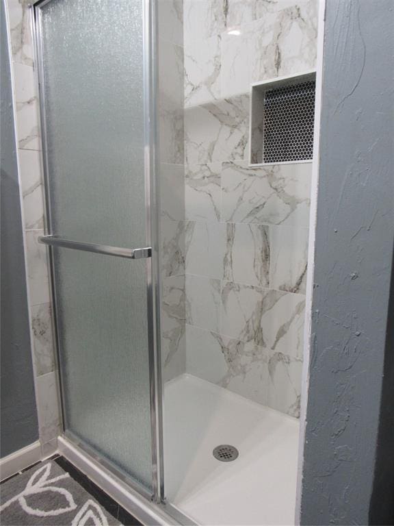 bathroom with visible vents, a textured wall, and a stall shower