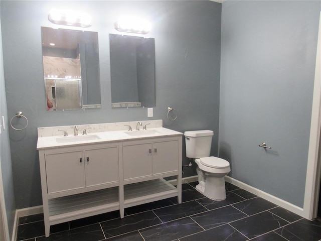 bathroom featuring double vanity, toilet, baseboards, and a sink