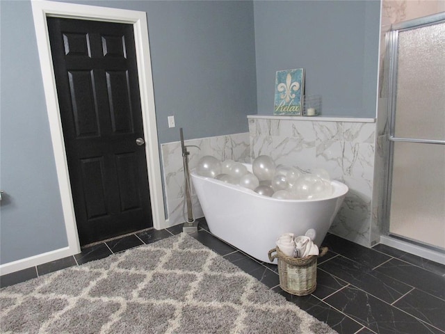 full bath with a freestanding bath, wainscoting, a stall shower, and tile walls