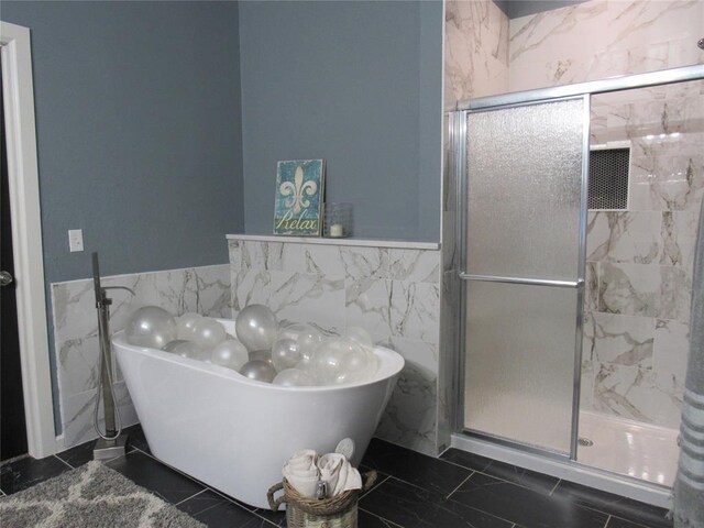 full bathroom featuring a soaking tub, tile walls, a stall shower, and wainscoting