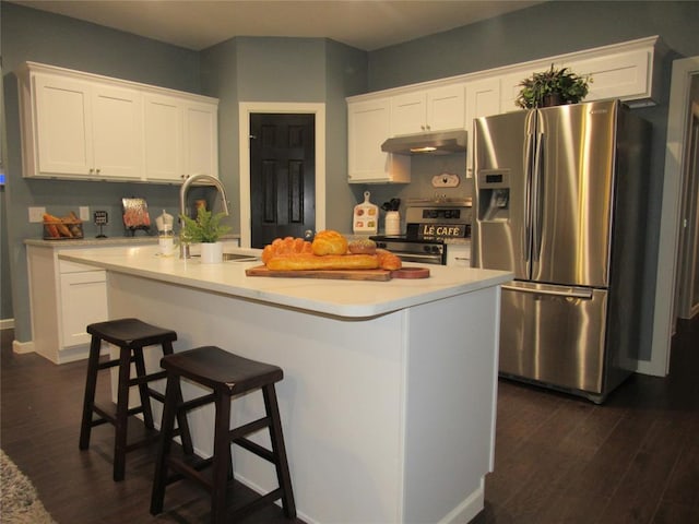 kitchen featuring dark wood-type flooring, stainless steel appliances, white cabinets, and a kitchen island with sink