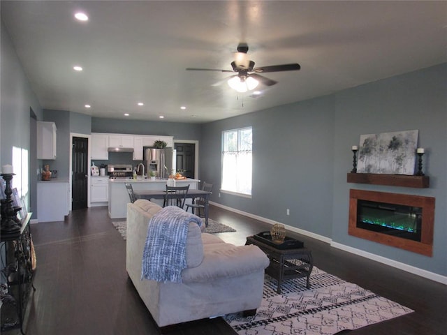 living room featuring ceiling fan, dark hardwood / wood-style floors, and sink