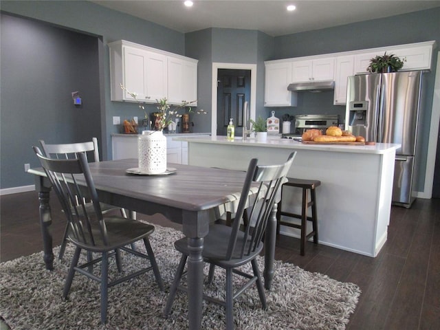 kitchen with stainless steel appliances, white cabinetry, a center island, and dark hardwood / wood-style floors