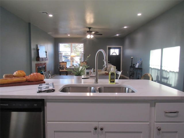 kitchen featuring a sink, stainless steel dishwasher, open floor plan, white cabinets, and a fireplace