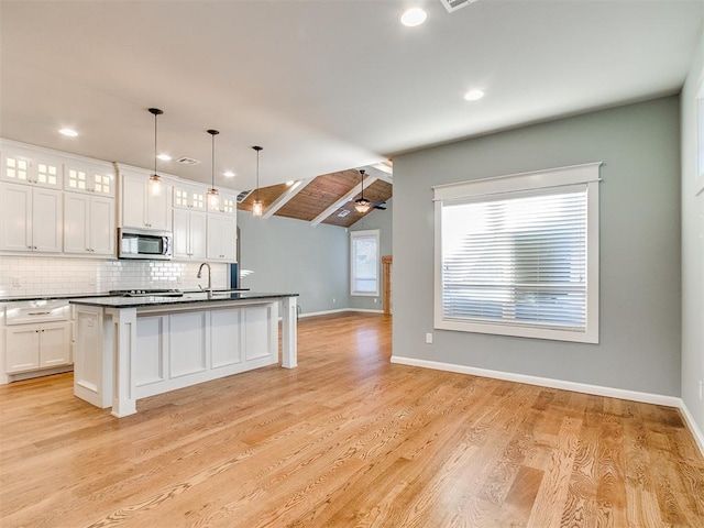 kitchen featuring decorative light fixtures, white cabinetry, wood ceiling, and an island with sink