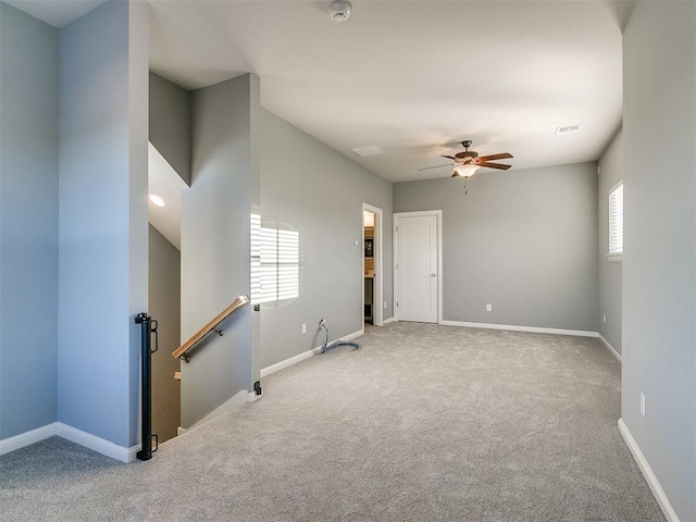 carpeted spare room featuring ceiling fan and a healthy amount of sunlight