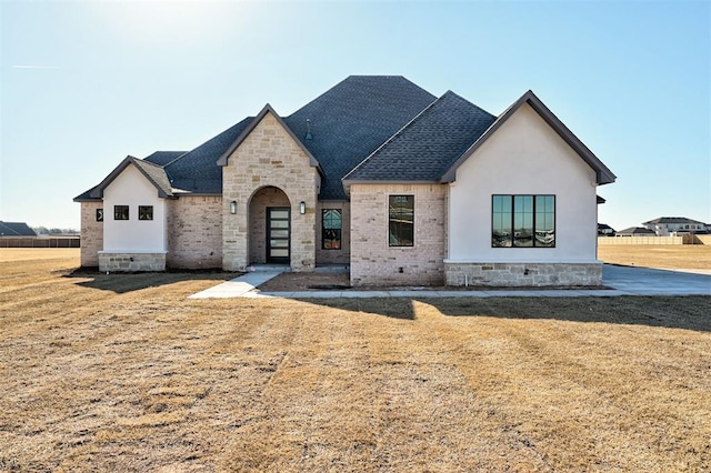 french country inspired facade featuring a front lawn