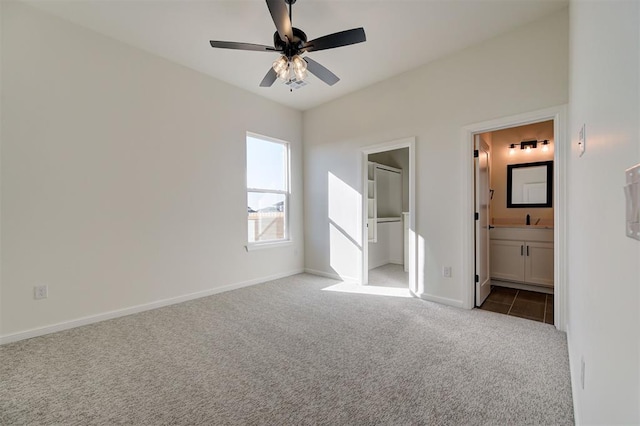 unfurnished bedroom with ceiling fan, light colored carpet, sink, and ensuite bath