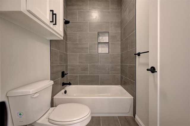 bathroom featuring wood-type flooring, tiled shower / bath, and toilet