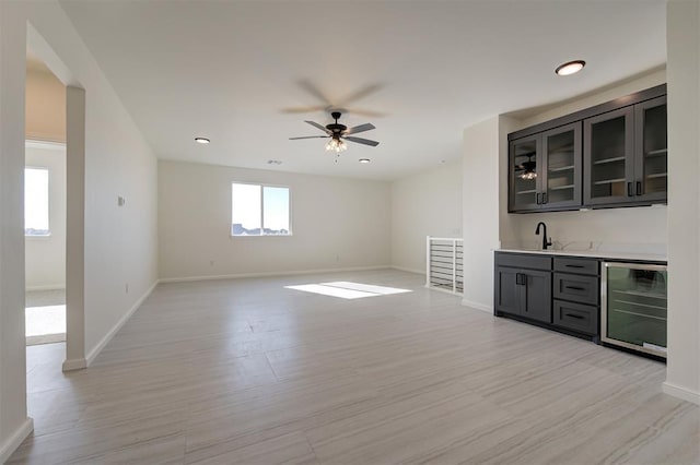 bar featuring sink, light hardwood / wood-style floors, beverage cooler, and ceiling fan