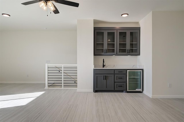 bar with wine cooler, ceiling fan, light hardwood / wood-style floors, and sink