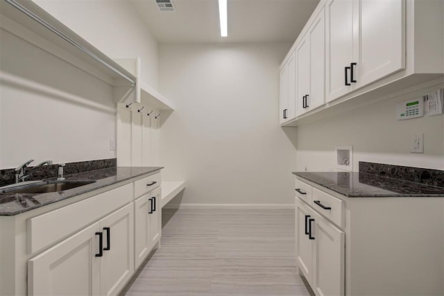 laundry room featuring sink, hookup for a washing machine, light hardwood / wood-style flooring, and cabinets