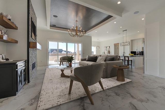 living room featuring an inviting chandelier, a tray ceiling, and a fireplace