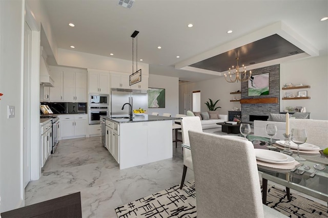 kitchen featuring white cabinetry, sink, built in appliances, and an island with sink