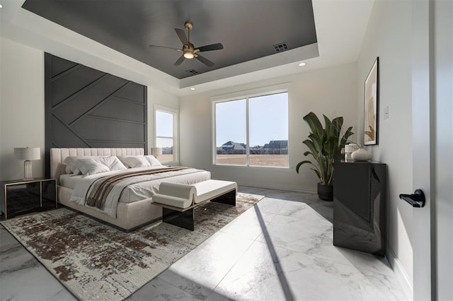 bedroom with ceiling fan and a raised ceiling