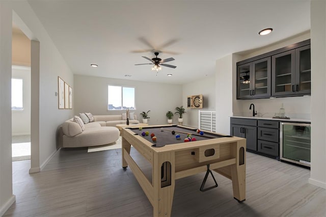 game room featuring wine cooler, wet bar, light hardwood / wood-style floors, and ceiling fan