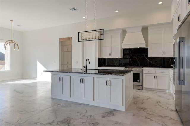 kitchen with white cabinetry, custom exhaust hood, appliances with stainless steel finishes, and a center island with sink