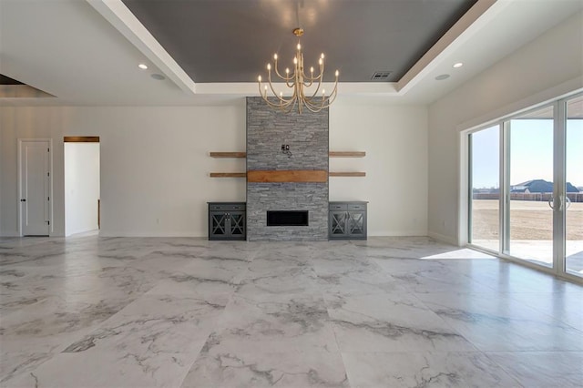 unfurnished living room featuring a high ceiling, a mountain view, a stone fireplace, a raised ceiling, and a chandelier