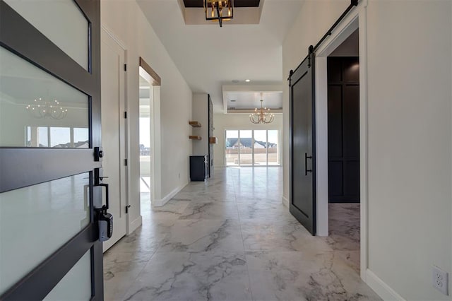 hallway featuring an inviting chandelier and a barn door