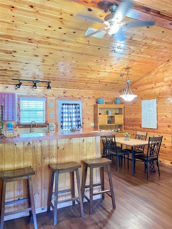 kitchen featuring lofted ceiling, a kitchen breakfast bar, dark hardwood / wood-style floors, ceiling fan, and kitchen peninsula