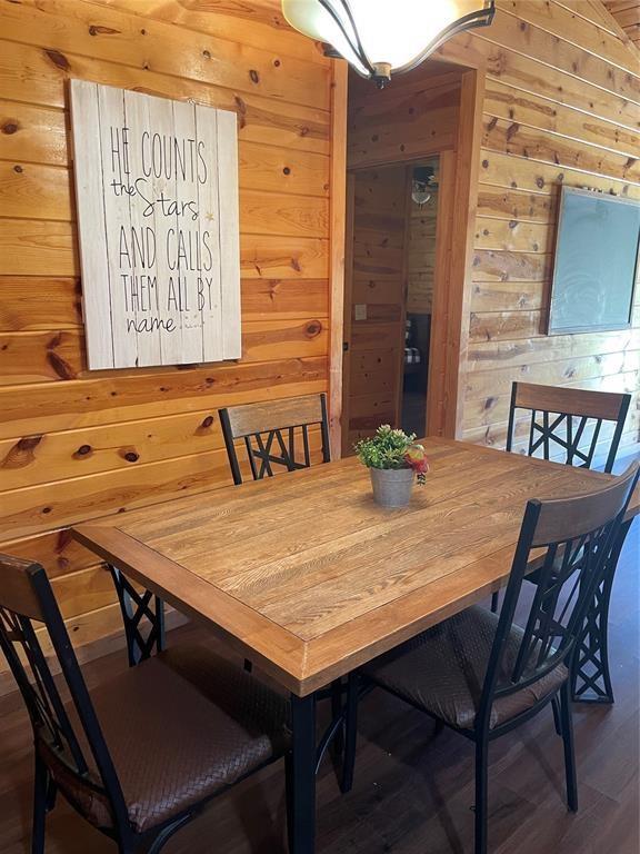 dining space with wood walls and wood-type flooring