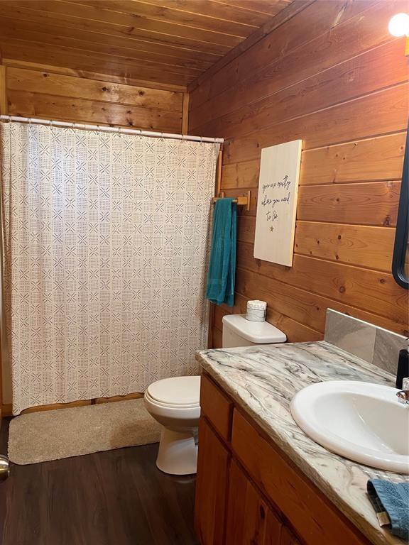 bathroom with vanity, wooden walls, wood-type flooring, wooden ceiling, and toilet