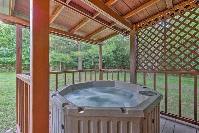 wooden terrace featuring a hot tub and a lawn