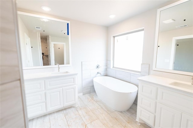 16024 Coneflower Dr, Edmond, OK 73013 - full bathroom with tile walls, a freestanding bath, two vanities, and recessed lighting