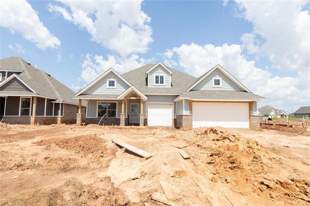 16024 Coneflower Dr, Edmond, OK 73013 - craftsman-style home featuring brick siding, a garage, a shingled roof, covered porch, and board and batten siding